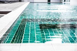 a swimming pool with green tiles on the floor at Corporate hotel suites at hartamas / mont kiara in Kuala Lumpur