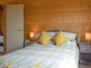 a bedroom with a bed with two yellow pillows at The Lodge in Great Easton