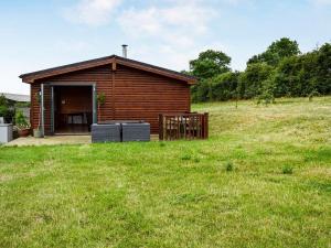 a small wooden cabin in a field with a grass yard at The Lodge in Great Easton