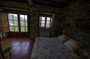 1 dormitorio con 1 cama en una habitación de piedra con ventanas en A Casua, en Boal