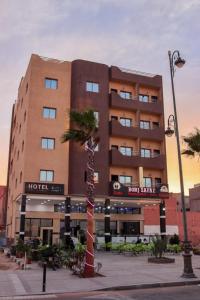 um edifício de hotel com uma palmeira em frente em HOTEL BORJ SAFAE LAAYOUNE em Laayoune