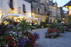 a courtyard with flowers and umbrellas in front of a building at Les Locations du Puits in Rochefort-en-Terre