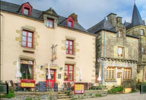 un gran edificio de piedra con puertas y ventanas rojas en Les Locations du Puits, en Rochefort-en-Terre