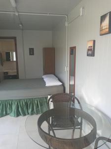 a room with a bed and a chair and a table at Kitbox PDR in Garopaba