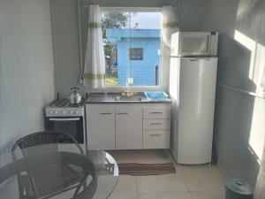 a small kitchen with a sink and a refrigerator at Kitbox PDR in Garopaba