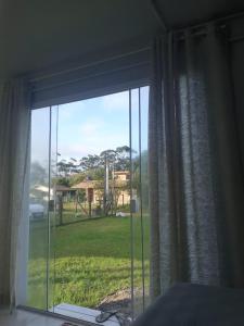 a bedroom window with a view of a yard at Kitbox PDR in Garopaba