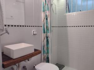 uma casa de banho branca com um lavatório e um WC em Pousada Éden em São Jorge