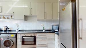 cocina con armarios blancos y nevera de acero inoxidable en San Lameer Style by Top Destinations Rentals en Southbroom
