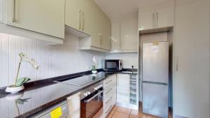 uma cozinha com armários brancos e um frigorífico em San Lameer Style by Top Destinations Rentals em Southbroom