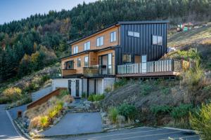 a house on the side of a hill at A Luckie Charm - 5-Bedroom Townhouse with Spectacular View in Queenstown
