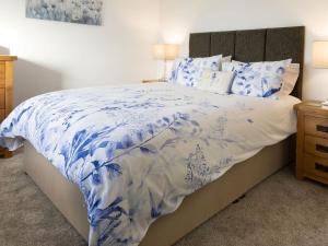 a bed with a blue and white comforter and pillows at Sunset View in Ardmaleish