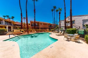 a swimming pool with a table and chairs and palm trees at Spring into Oasis Permit# 5140 in Palm Springs