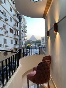 a balcony with two chairs and a view of the pyramids at Asma Pyramids View in Cairo