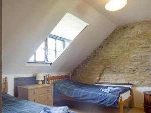 a attic bedroom with two beds and a stone wall at Doward Farm in Symonds Yat