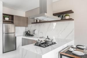 uma cozinha branca com duas panelas no fogão em Casa Requinte Com piscina 02 no Balneário Camboriú