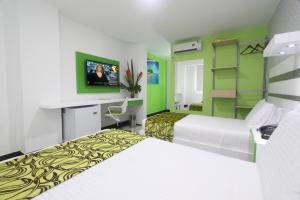 a hotel room with two beds and a tv at Hotel Genova Prado in Barranquilla