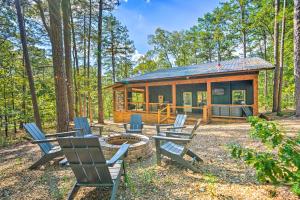 a cabin in the woods with chairs and a fire pit at Chic Broken Bow Cabin with Hot Tub and Gas Grill! in Broken Bow