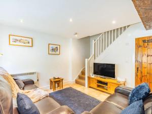 a living room with a couch and a television at Claro Cottage - Uk37450 in Pateley Bridge