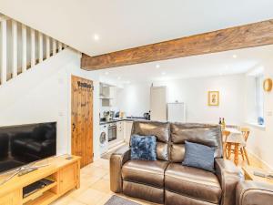 a living room with a leather couch and a television at Claro Cottage - Uk37450 in Pateley Bridge