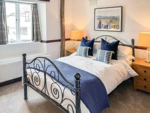 a bedroom with a large bed with blue pillows at Tubs Cottage in Kingsteignton