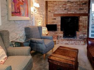 sala de estar con 2 sillas y chimenea en Tubs Cottage, en Kingsteignton