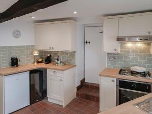 a kitchen with white cabinets and a counter top at Tubs Cottage in Kingsteignton