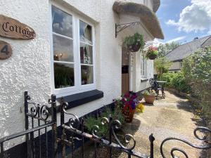 a white building with a window and a fence at Tubs Cottage in Kingsteignton