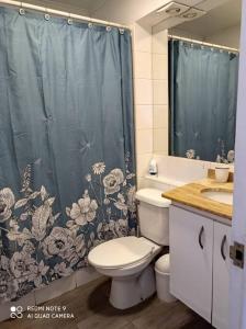 a bathroom with a toilet and a shower curtain at Depto Oceanic III La Serena in La Serena