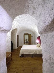 een slaapkamer met een bed in een stenen muur bij Casas Cueva La Tala in Guadix