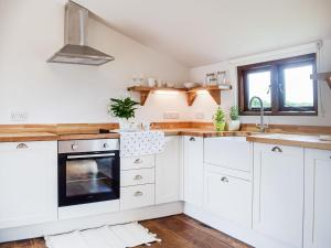 a kitchen with white cabinets and a stove at The Summerhouse - Uk34933 in Baschurch