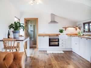 a kitchen with white cabinets and a table and chairs at The Summerhouse - Uk34933 in Baschurch