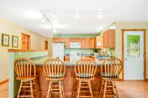 una cocina con 3 taburetes y una barra en Ashton House, en Phelps