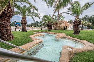 une piscine avec des palmiers dans un parc dans l'établissement The Wharf 811, à Orange Beach