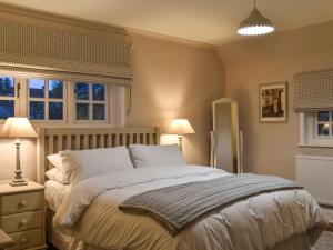 a bedroom with a large bed and two lamps at Cobblers Cottage in Petworth
