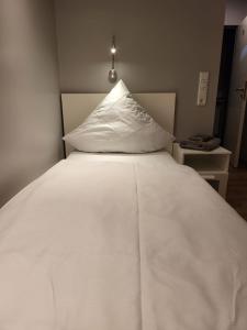 a white bed with a white pillow on top of it at "Anderer´s" Gasthaus & Hotel Hohne in Hohne