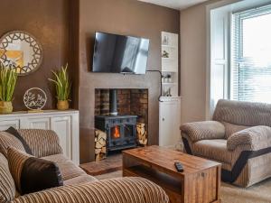 a living room with a fireplace with a television above it at Sunnyside in New Galloway