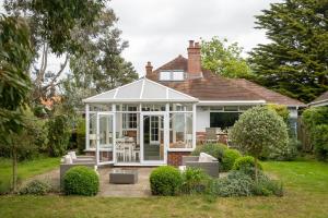 a house with a conservatory in the yard at Pinewood - Aldeburgh Coastal Cottages in Aldeburgh