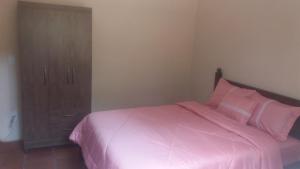 a bedroom with a pink bed and a cabinet at Campo dos Sonhos in Serra Negra