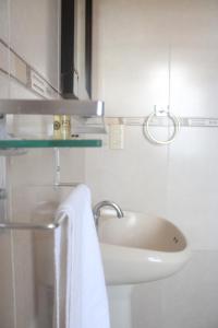 a white bathroom with a sink and a towel at Hotel Alika in Zacatecas