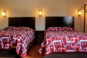 Cette chambre d'hôtel comprend 2 lits avec des couvertures rouges et blanches. dans l'établissement Hotel Alika, à Zacatecas