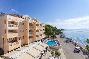 a building with a swimming pool next to the ocean at Aparthotel Milenij in Ba&scaron;ka Voda