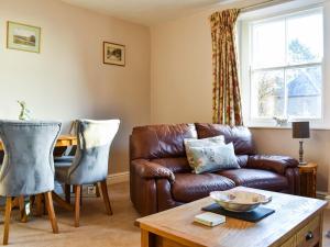 a living room with a leather couch and a table at Staffield Cottage in Kirkoswald