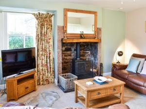 a living room with a fireplace and a couch at Staffield Cottage in Kirkoswald