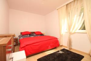 a bedroom with a red bed and a window at Apartments with a parking space Icici, Opatija - 7785 in Ičići