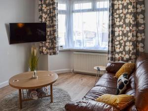 sala de estar con sofá de cuero y mesa en Joes Place, en Mablethorpe