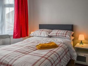1 cama con manta amarilla y cortina roja en Joes Place, en Mablethorpe