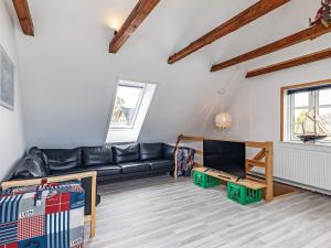 Holiday home Rudkøbing XIX في Spodsbjerg: غرفة معيشة مع أريكة جلدية سوداء وتلفزيون
