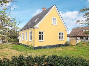 żółty dom z czarnym dachem na podwórku w obiekcie Holiday home Rudkøbing XIX w mieście Spodsbjerg