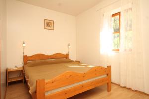 1 dormitorio con cama de madera y ventana en Family friendly seaside apartments Susak, Losinj - 8050 en Susak