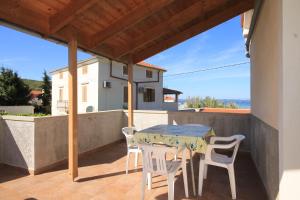 patio con mesa y sillas en el balcón en Family friendly seaside apartments Susak, Losinj - 8050 en Susak